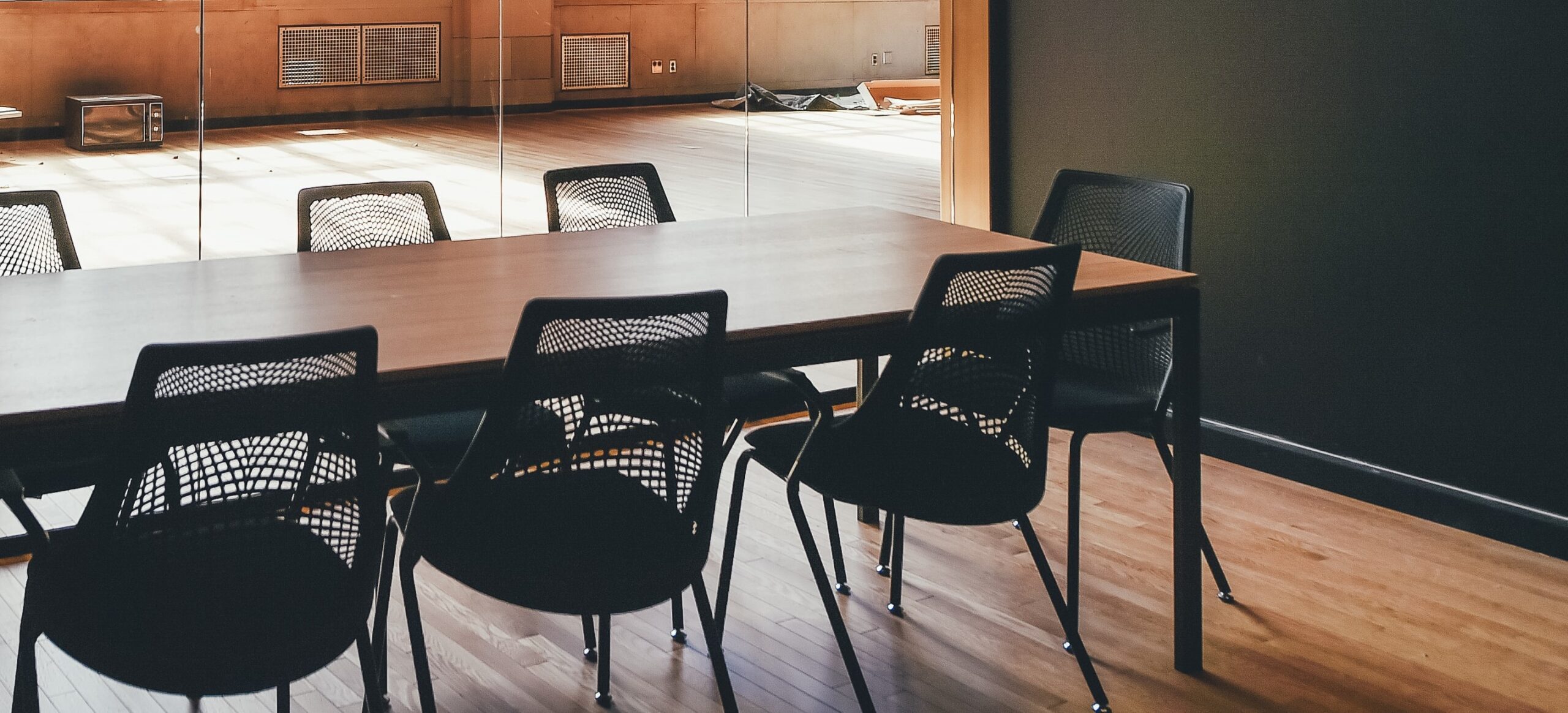 long wood table seven black mesh chairs