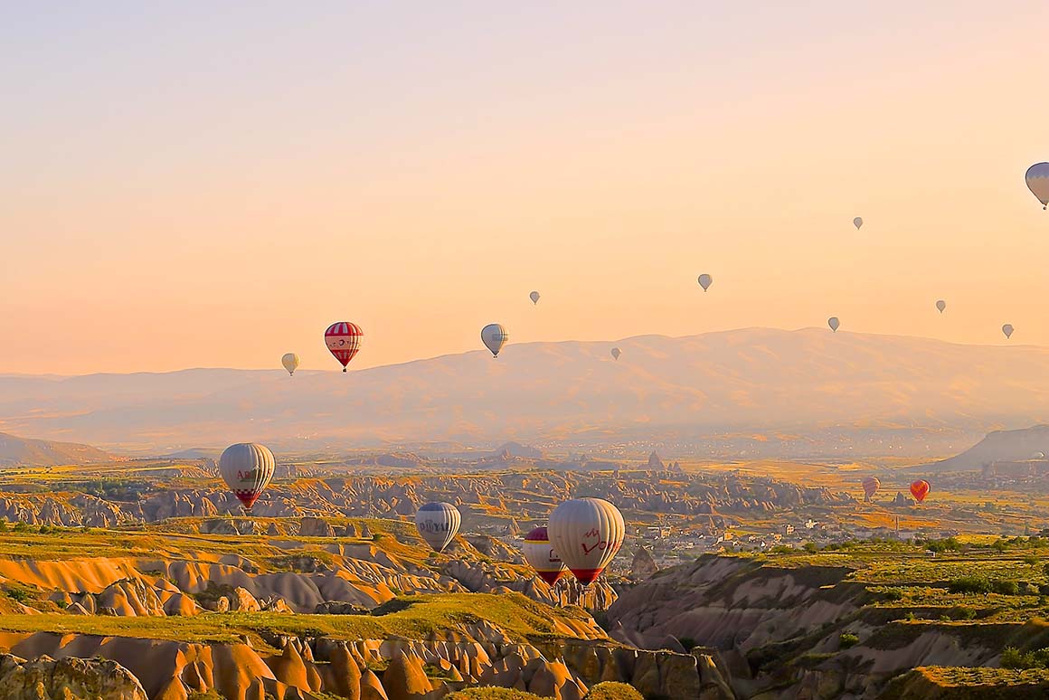 seventeen hot air balloons over rocky mountainous landscape